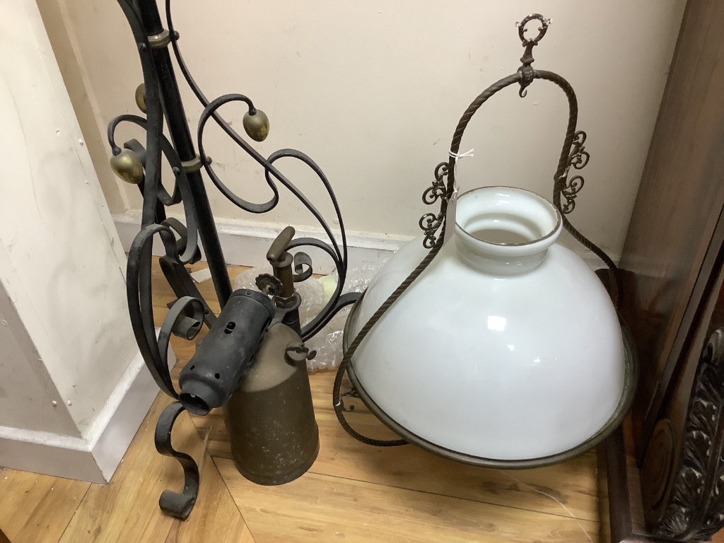 A wrought iron oil-fired floor lamp with reservoir and chimney a hanging Aladdin oil lamp with chimney and shade, and a large vintage brass blow-lamp